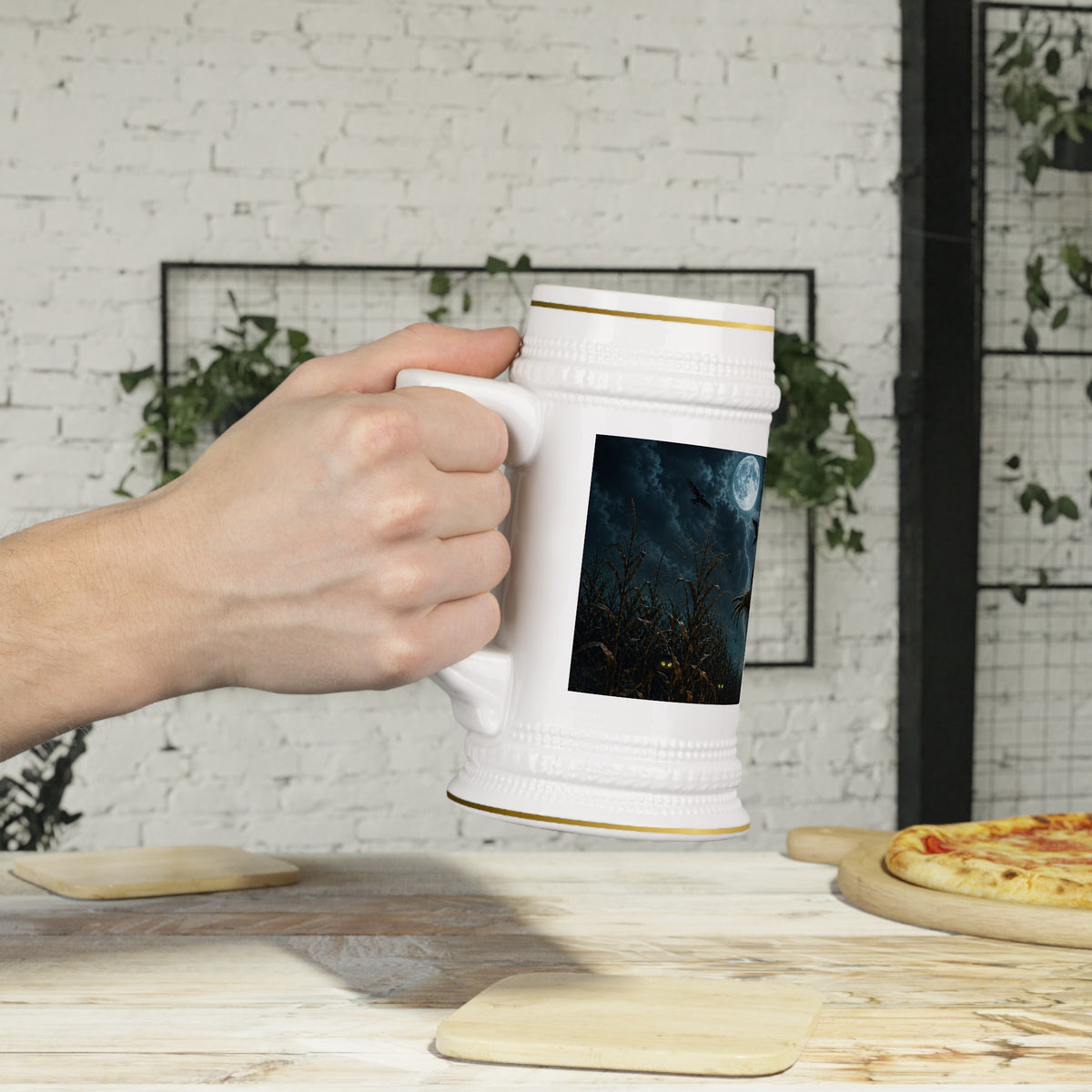 A hand holds the 22oz gold-trimmed ceramic stein beside a dining table, showing the moonlit cornfield artwork and mug size.