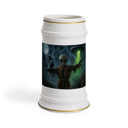 Front view of a white ceramic stein with gold trim, showing an alien scarecrow, ravens, a full moon and a green UFO beam.